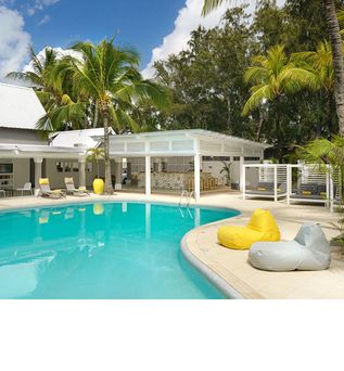 Poolbereich des Hotels Tropical Attitude auf Mauritius mit Liegestühlen, gelben und grauen Sitzsäcken, umgeben von weißen Gebäuden und Palmen.