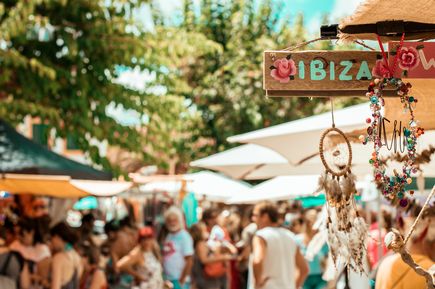 Bunter Hippie-Markt auf Ibiza mit vielen Menschen, Verkaufsständen, Schmuck und Traumfängern im Vordergrund