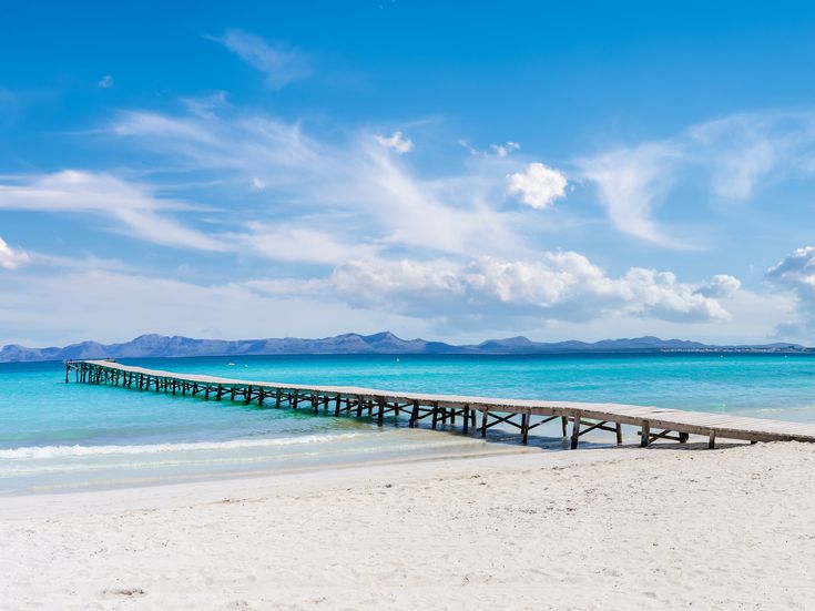 Strand Playa de Muro auf Mallorca mit weißem Sand, türkisblauem Meer und einem langen Holzsteg ins Wasser