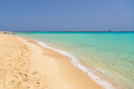 Mahmya Strand in Ägypten mit hellem Sand und klarem türkisfarbenem Wasser unter blauem Himmel, Menschen im Wasser und am Ufer