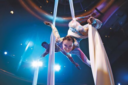 Artistik-Show im Theatrium der AIDAluna mit zwei Akrobat*innen, die in weißen Tüchern hoch über der Bühne performen, eindrucksvoll beleuchtet durch blaue und violette Scheinwerfer