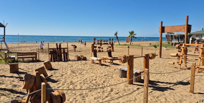 Outdoor-Fitnessgeräte aus Holz auf Sandstrand mit Meer und blauem Himmel im Hintergrund, Armella Hill Hotel & Spa, Türkei.