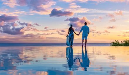 Paar am Infinity-Pool während des Sonnenuntergangs im Abendlicht 