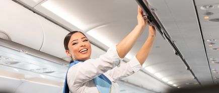 Kabinencrew von Discover Airlines schließt die Gepäckfächer in einem Airbus A320 während des Boardings in der Flugzeugkabine