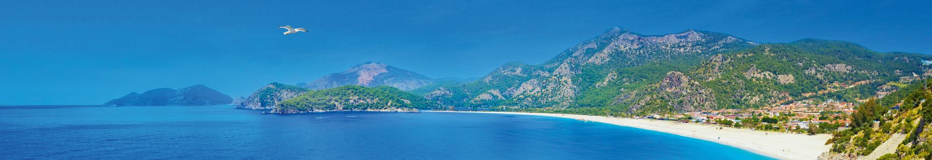 Panoramablick auf die Küste von Fethiye in der Türkei mit blauem Meer, Sandstrand und grünen Bergen