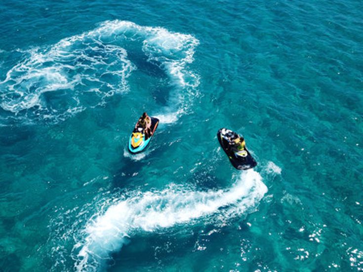 Zwei Jetskis ziehen Spuren auf dem klaren blauen Meer, aufgenommen aus der Luft