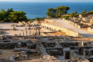 Ruinen der antiken Stadt Kamiros auf Rhodos mit Blick auf das Meer und Bäume im Hintergrund.
