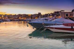Jachten im Hafen von El Gouna in Ägypten bei Sonnenuntergang mit beleuchteten Gebäuden im Hintergrund