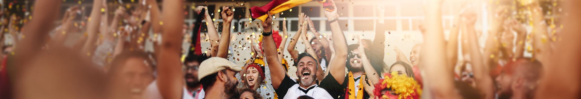 Gruppe jubelnder Deutschland-Fans mit erhobenen Armen und Konfetti in der Luft
