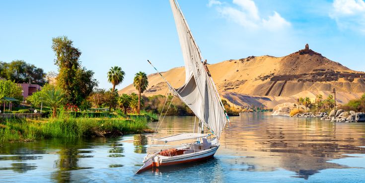 Traditionelles Segelboot auf dem Nil vor Palmen und Sanddünen