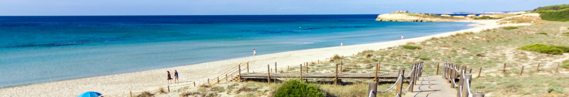 Holzsteg mit Seilgeländer führt durch die Dünen zum Strand von Son Bou auf Menorca mit hellem Sand und türkisblauem Meer