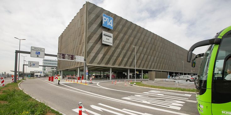 Flughafen Stuttgart Parkhaus P14 mit Busterminal, moderne Fassadenarchitektur, Zufahrtsstraße mit Beschilderung und haltendem Shuttlebus im Vordergrund