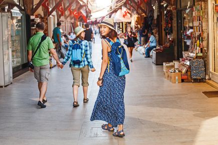 Touristen spazieren durch eine türkische Einkaufsstraße mit kleinen Läden und vielen roten Flaggen