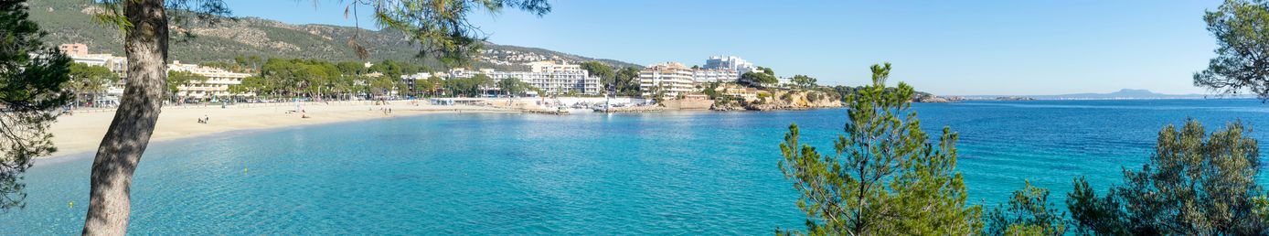 Panorama vom Strand von Magaluf auf Mallorca mit türkisfarbenem Meer, Hotelanlagen und grünen Hügeln