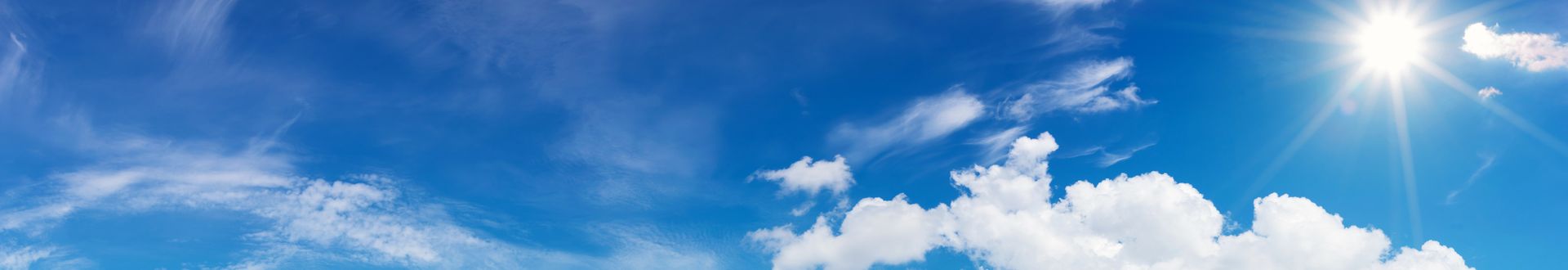 Blauer Himmel mit weißen Wolken und strahlender Sonne