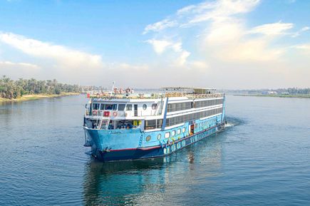 MS Magic I Nilkreuzfahrtschiff auf dem Nil mit Palmen am Ufer und bewölktem Himmel