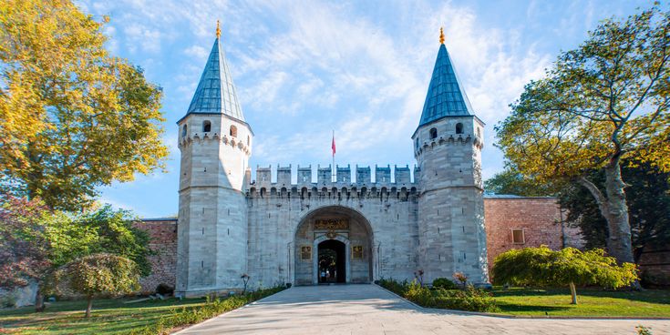 Haupteingang des Topkapi-Palasts in Istanbul mit zwei hohen Türmen und historischer Steinarchitektur, umgeben von Bäumen