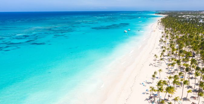 Luftaufnahme des langen weißen Sandstrands mit Palmen und türkisfarbenem Meer an der Strand Arena Gorda in der Dominikanischen Republik