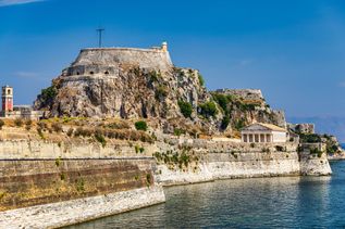 Alte venezianische Festung auf felsigem Hügel mit Wehrmauern am Wasser unter blauem Himmel