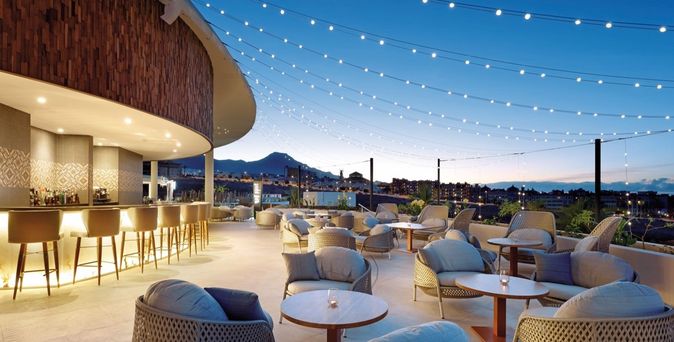 Frau mit Strohhut am Strand vor blauem Meer