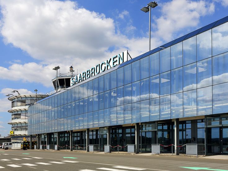Außenansicht des Terminals am Flughafen Saarbrücken, moderne Glasfassade mit gut sichtbarem Schriftzug „Saarbrücken“, Tower und Vorfahrtbereich
