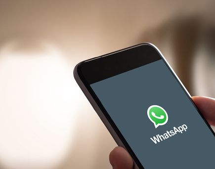 Hand hält Smartphone mit geöffneter WhatsApp-App auf dem Bildschirm