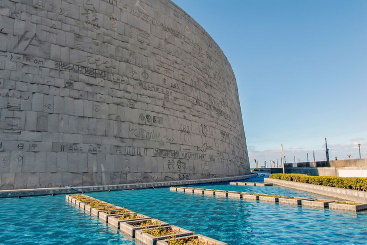 Moderne Außenansicht der Bibliothek von Alexandria mit Reliefs und Wasserbecken im Vordergrund