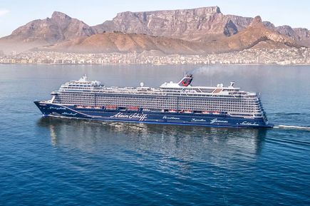 Das Kreuzfahrtschiff „Mein Schiff 2“ fährt vor der Kulisse des Tafelbergs und der Stadt Kapstadt über das ruhige Meer
