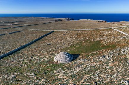Ein Talayot auf Menorca erhebt sich aus einer weiten Steinlandschaft und zeigt die typische Bauweise aus Trockenstein