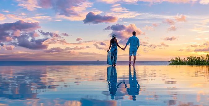 Paar am Infinity-Pool während des Sonnenuntergangs im Abendlicht 