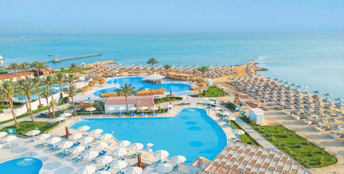 Blick auf das SUNRISE Azalea Aqua Park Resort mit großzügigen Poolanlagen, Palmen, Sandstrand und zahlreichen Liegen direkt am Meer.