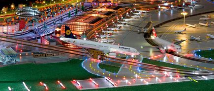 Detailreiche Modellschau des Flughafens Hamburg bei Nacht mit beleuchteten Landebahnen, Terminalgebäuden und einem Lufthansa-Flugzeug als Ausstellungsstück im Miniaturformat