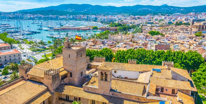Luftaufnahme des Königspalasts La Almudaina in Palma de Mallorca mit Blick auf den Yachthafen, die Altstadt und die umliegenden Berge