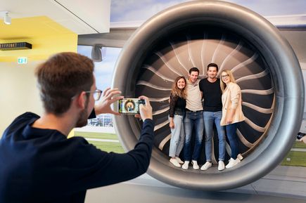 Besucher im Erlebnisbereich SkyLand am Flughafen Stuttgart posieren für ein Erinnerungsfoto in einem begehbaren Flugzeugtriebwerk