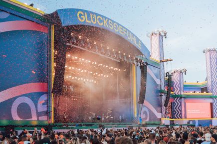 Große Festivalbühne beim Glücksgefühle Festival mit Lichteffekten, Konfetti und zahlreichen Besucherinnen und Besuchern vor der Bühne.