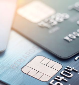 Nahaufnahme von zwei Kreditkarten, eine blaue und eine schwarze, mit sichtbaren Chip- und Prägezahlen.