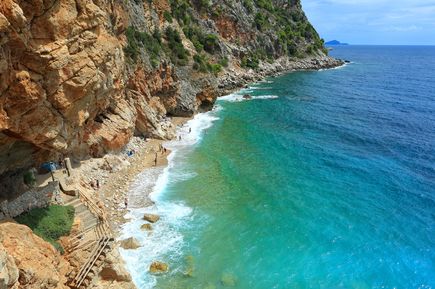 Die Plaža Pasjača in Kroatien mit steilen Felsklippen, schmalem Kiesstrand, türkisfarbenem Adriatischen Meer und einem in den Felsen angelegten Treppenweg