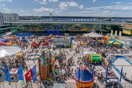 Kinderfest am Flughafen Stuttgart mit zahlreichen Aktionsflächen, Spielstationen, Hüpfburgen und Besuchern auf dem Vorplatz des modernen Terminalgebäudes