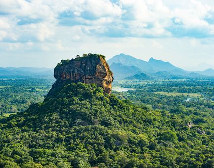Felsformation Sigiriya in Sri Lanka, umgeben von dichtem Grün und Bergen im Hintergrund