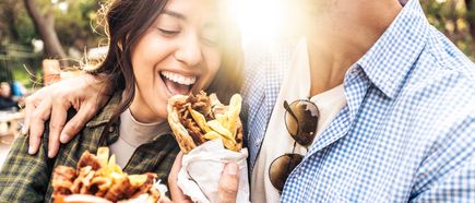 Lachendes Paar genießt frische Kebab-Wraps im Sonnenschein