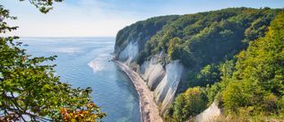 Blick auf die berühmten weißen Kreidefelsen im Nationalpark Jasmund auf Rügen mit bewaldeten Steilküsten und der Ostsee entlang der Küste.