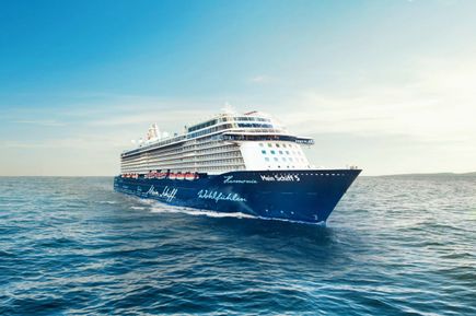 Die Mein Schiff 5 von TUI Cruises fährt über das offene Meer; das dunkelblaue Design mit weißer Handschrift und der moderne Schiffsbau sind gut zu sehen