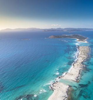 Luftaufnahme der schmalen Sandbank Ses Illetes auf Formentera, umgeben von türkisblauem Meer und mit Blick auf die Nachbarinseln