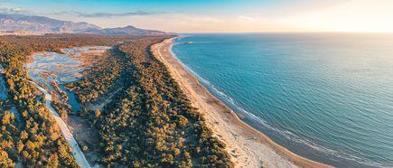 Luftaufnahme des Patara Beach in Antalya, Türkei, mit langem Sandstrand, türkisblauem Meer und grünen Pinienwäldern bei Sonnenuntergang