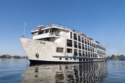 Das weiße Nilkreuzfahrtschiff MS Kleos mit mehreren Decks und Fenstern auf dem Nil, blauer Himmel im Hintergrund