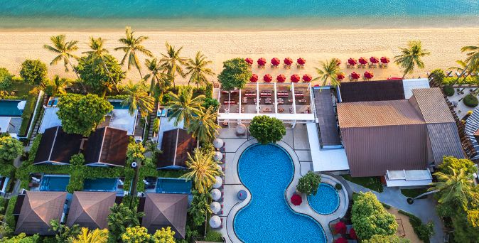 Luftaufnahme des NH Collection Samui Peace Resort auf Koh Samui mit tropischer Gartenanlage, Poolbereich, Villen, Palmen und direkter Lage am weißen Sandstrand mit türkisblauem Meer