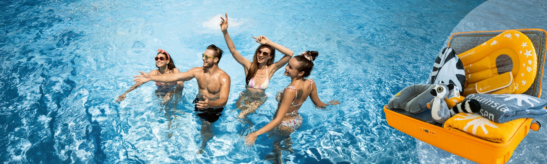 Vier junge Menschen in Badebekleidung, die im Wasser eines Schwimmbeckens stehen und lachen, davor ein geöffneter oranger Koffer mit verschiedenen Reiseutensilien wie Handtüchern, aufblasbarem Surfboard, Tickettasche, Plüschtier etc.