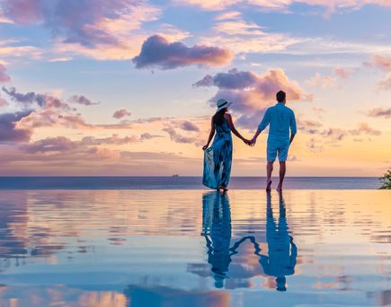 Paar am Infinity-Pool während des Sonnenuntergangs im Abendlicht 