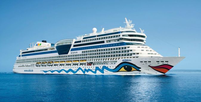 Die AIDAblu fährt auf offenem Wasser unter blauem Himmel, gut erkennbar mit der bekannten Wellen- und Augenbemalung am Schiffsrumpf