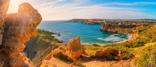 Blick auf die Għajn Tuffieħa Bay auf Malta mit steilen Küstenhängen, Felsformationen und einer geschützten Bucht am Mittelmeer